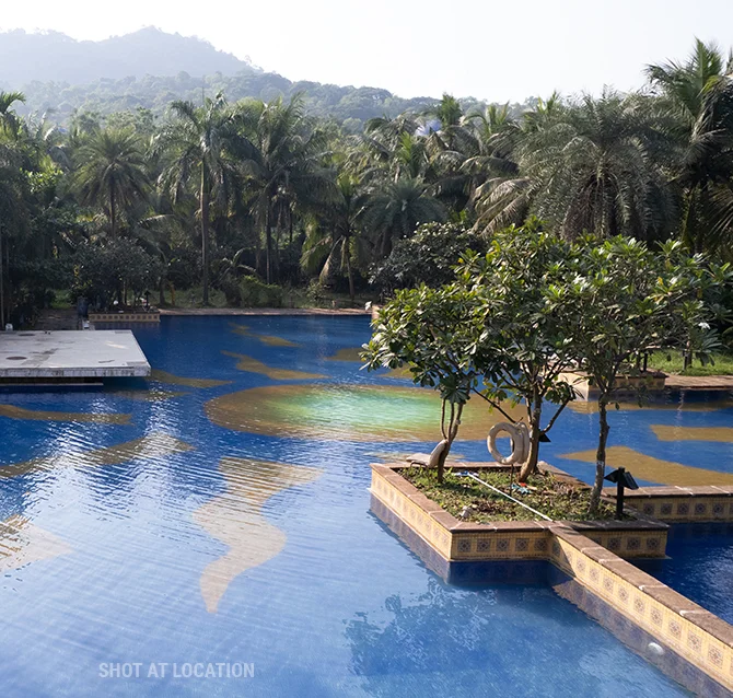 A vast swimming pool encircled by greenery and mountains, providing a peaceful and idyllic outdoor setting.