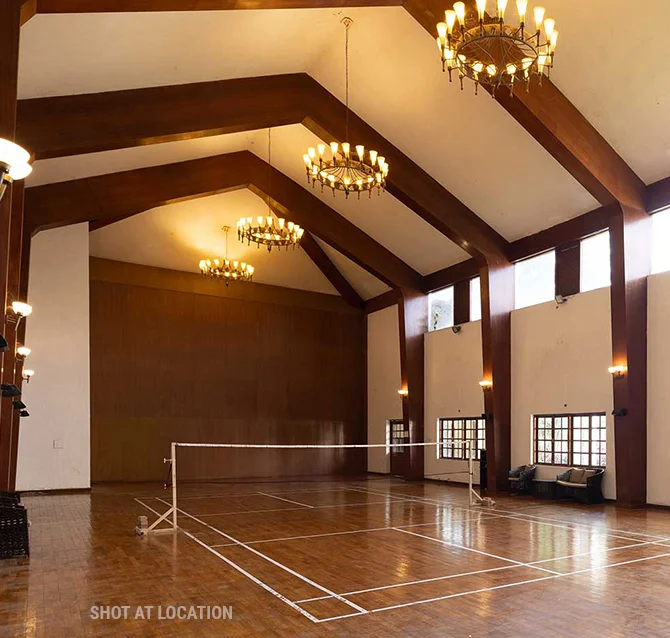 A large room with a tennis court, complemented by stunning chandeliers that add sophistication to the space.