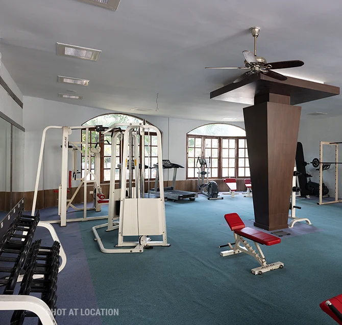 Interior of a gym showcasing exercise equipment and a ceiling fan, designed for an optimal workout environment.