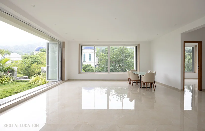 A spacious living room featuring large windows that allow natural light, complemented by a central table for gatherings.