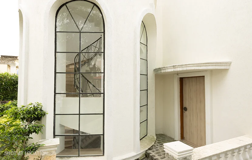 A charming white house showcasing a spacious window and a front door, surrounded by a serene outdoor environment.