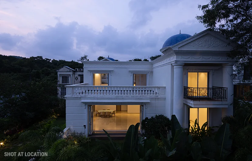 A white house featuring a blue dome, illuminated by the soft light of dusk, creating a serene evening atmosphere.