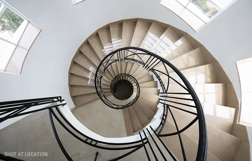 A beautifully designed spiral staircase spirals upward in a white building, emphasizing modern architecture and aesthetic appeal.