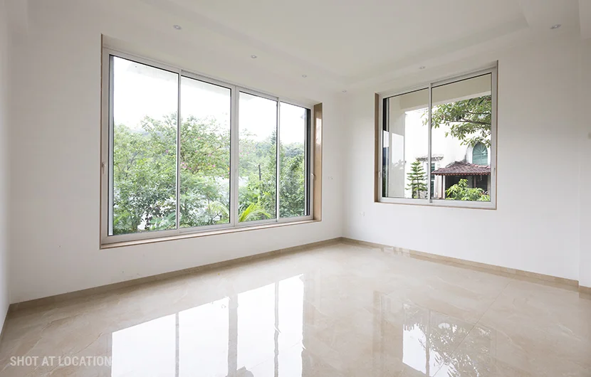 A spacious, vacant room with expansive windows and clean white walls, offering a sense of openness and light.