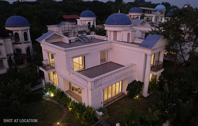 A spacious white house adorned with blue domes, glowing softly at night, highlighting its architectural beauty under the stars.