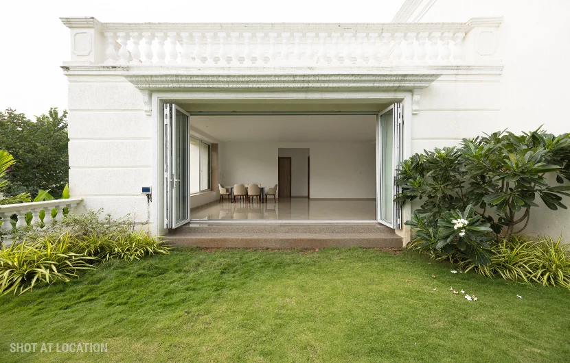 A white house displaying a wide open door, complemented by a vibrant green lawn in front.